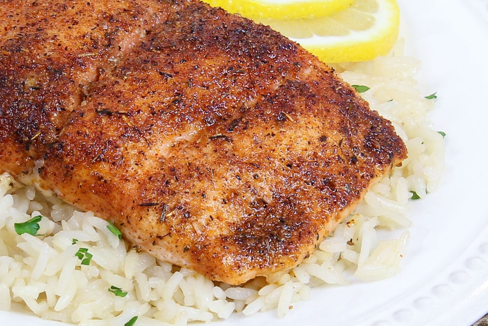 Baked Blackened Salmon recipe close up on a white plate with lemons.
