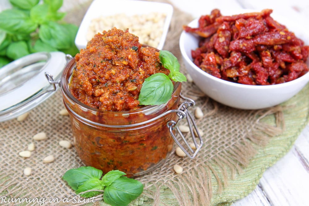 Sun Dried Tomato Pesto recipe in a glass jar with sun dried tomato on the side.