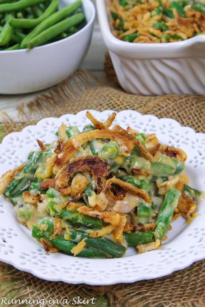 Cheesy Green Bean Casserole with fresh green beans on a white plate.