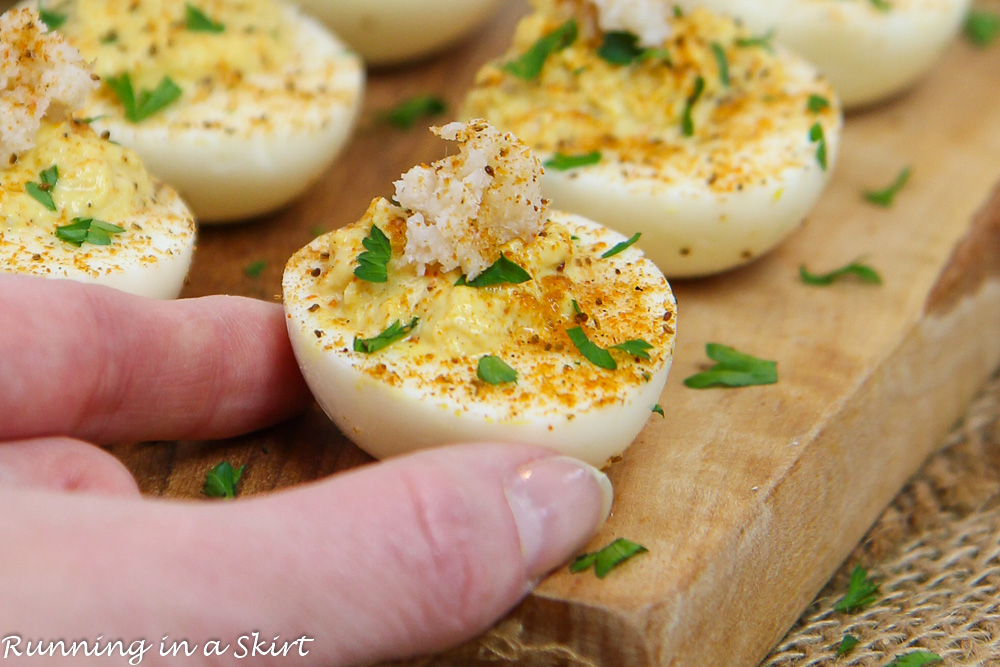 Crab Deviled Eggs with hand grabbing it.